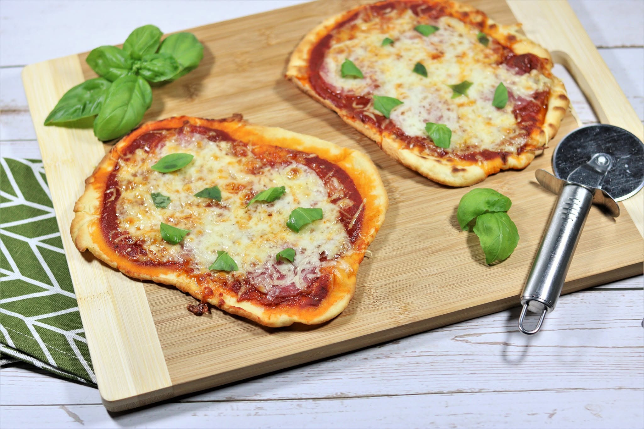 Two homemade pizzas with basil