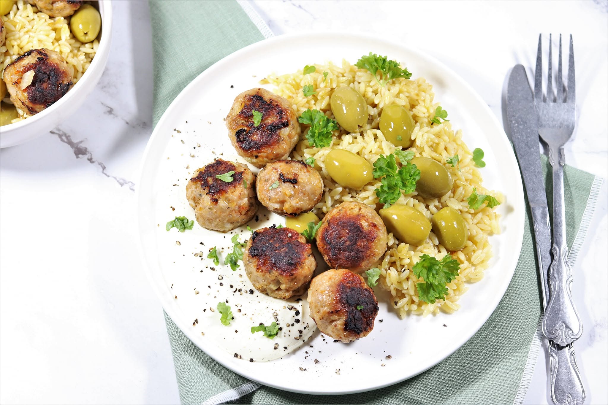 A plate of grains, browned bites and green grapes